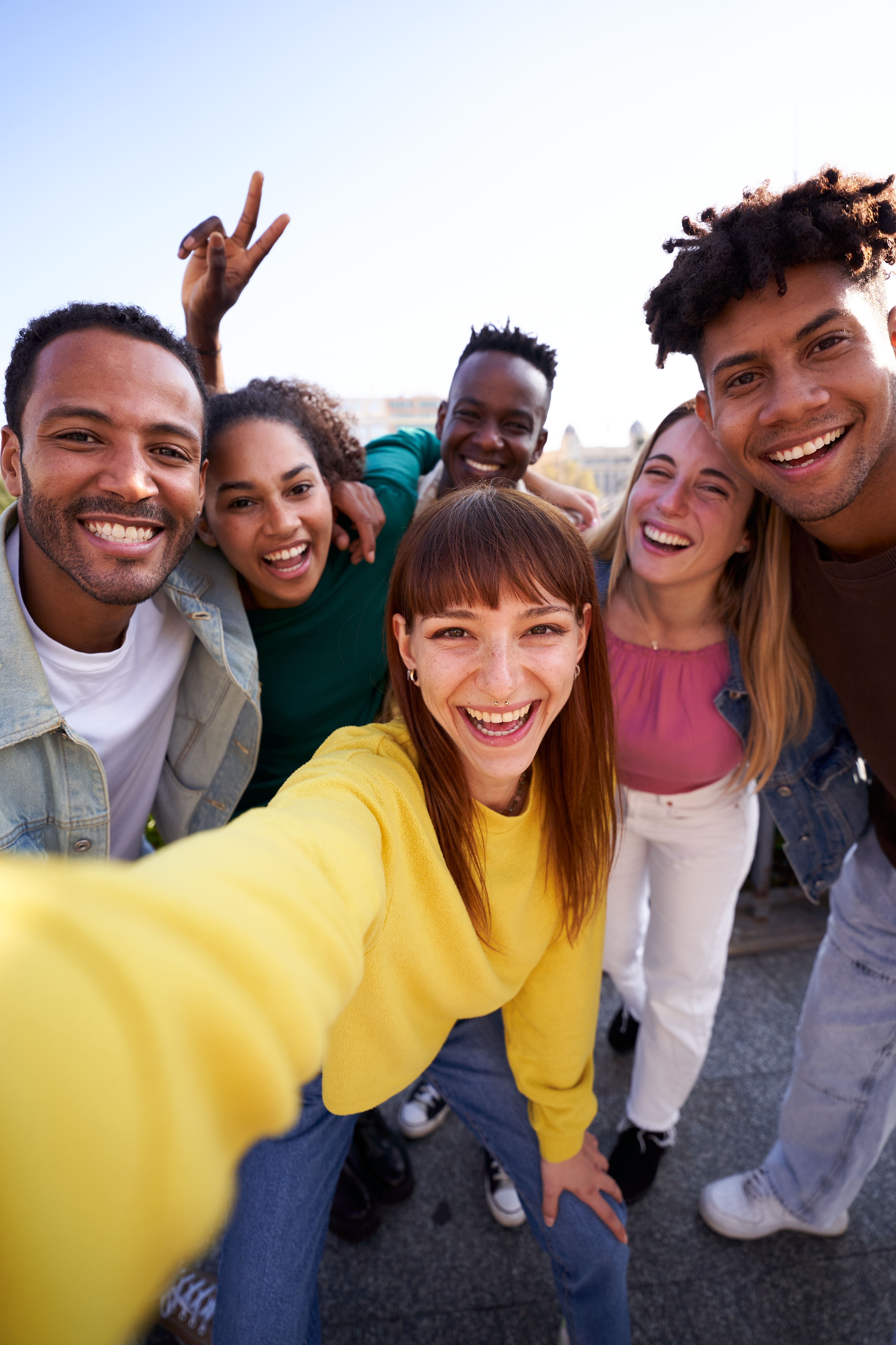 Un groupe de jeunes divers prenant un selfie à l'extérieur, s'amusant par une journée ensoleillée.