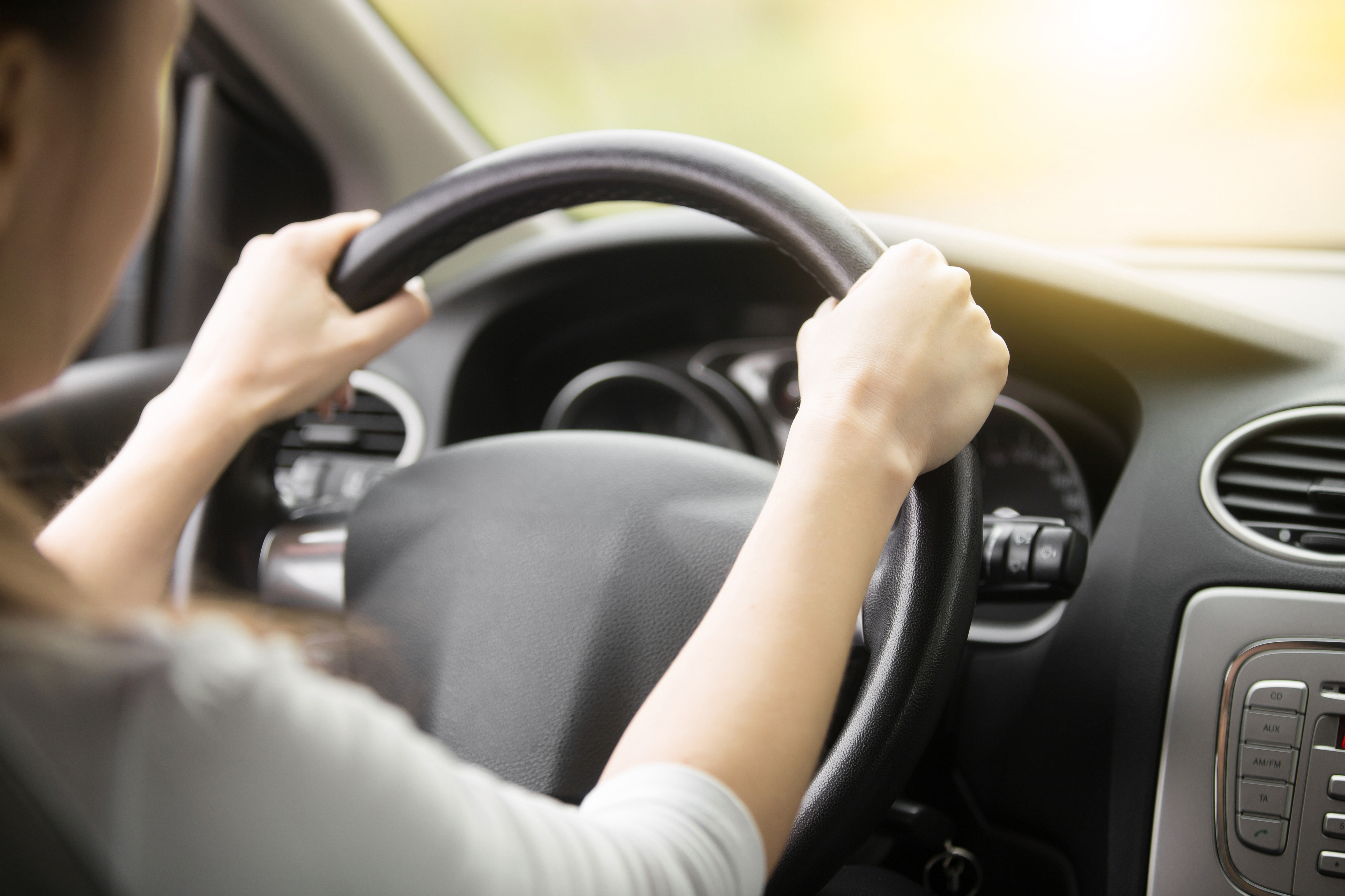 Two hands gripping a steering wheel in a car.