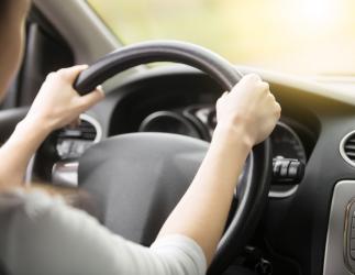 Two hands on a steering wheel. 
