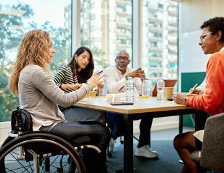 group of people sitting around a table discuing work.