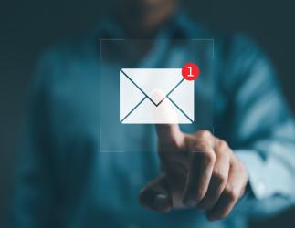 Une personne pointant vers un symbole de notification par courrier électronique flottant.