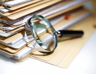 pile of documents next to a magnifying glass.