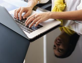 A person’s hands typing on a laptop.