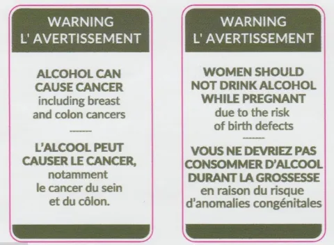 Two bilingual warning labels in English and French about alcohol consumption risks. Labels read: Warning. Alcohol can cause cancer, including breast and colon cancer. And: Warning. Women should not drink alcohol while pregnant due to the risk of birth defects. 