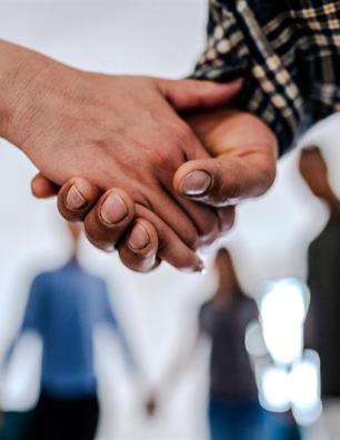 Close-up of people holding hands supporting each other during a group session.