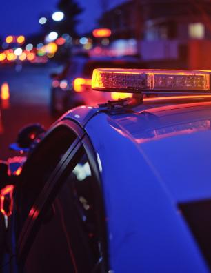 Voiture de police aux gyrophares allumés arrêtée sur le bord de la route.