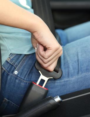 A person’s hand buckling their seatbelt.