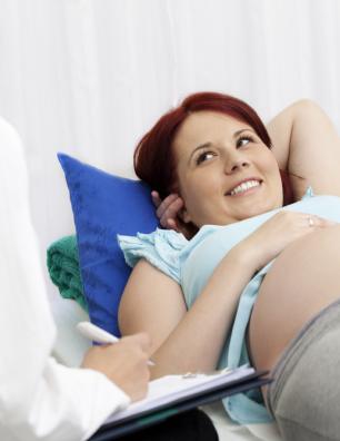 Femme enceinte couchée sur le dos, à côté d’une professionnelle de la santé.