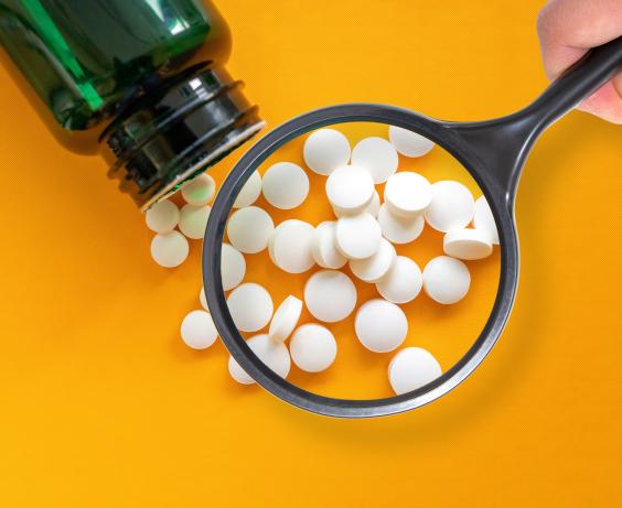 Magnifying glass looking at an opened bottle of phamaceuticals.
