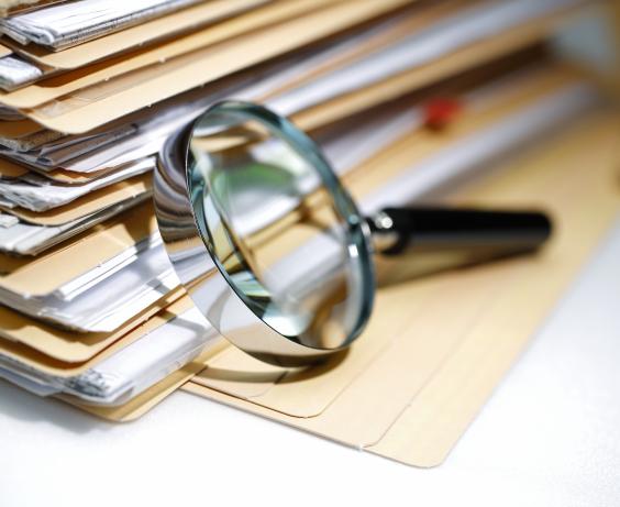 pile of documents next to a magnifying glass.