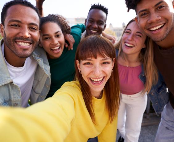 Group of diverse youth taking a selfie outdoors, having fun in sunny day. 