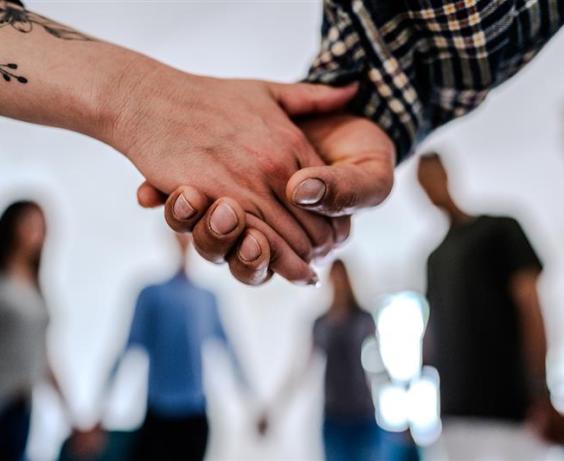 Gros plan de personnes se tenant par la main pendant une séance de groupe.